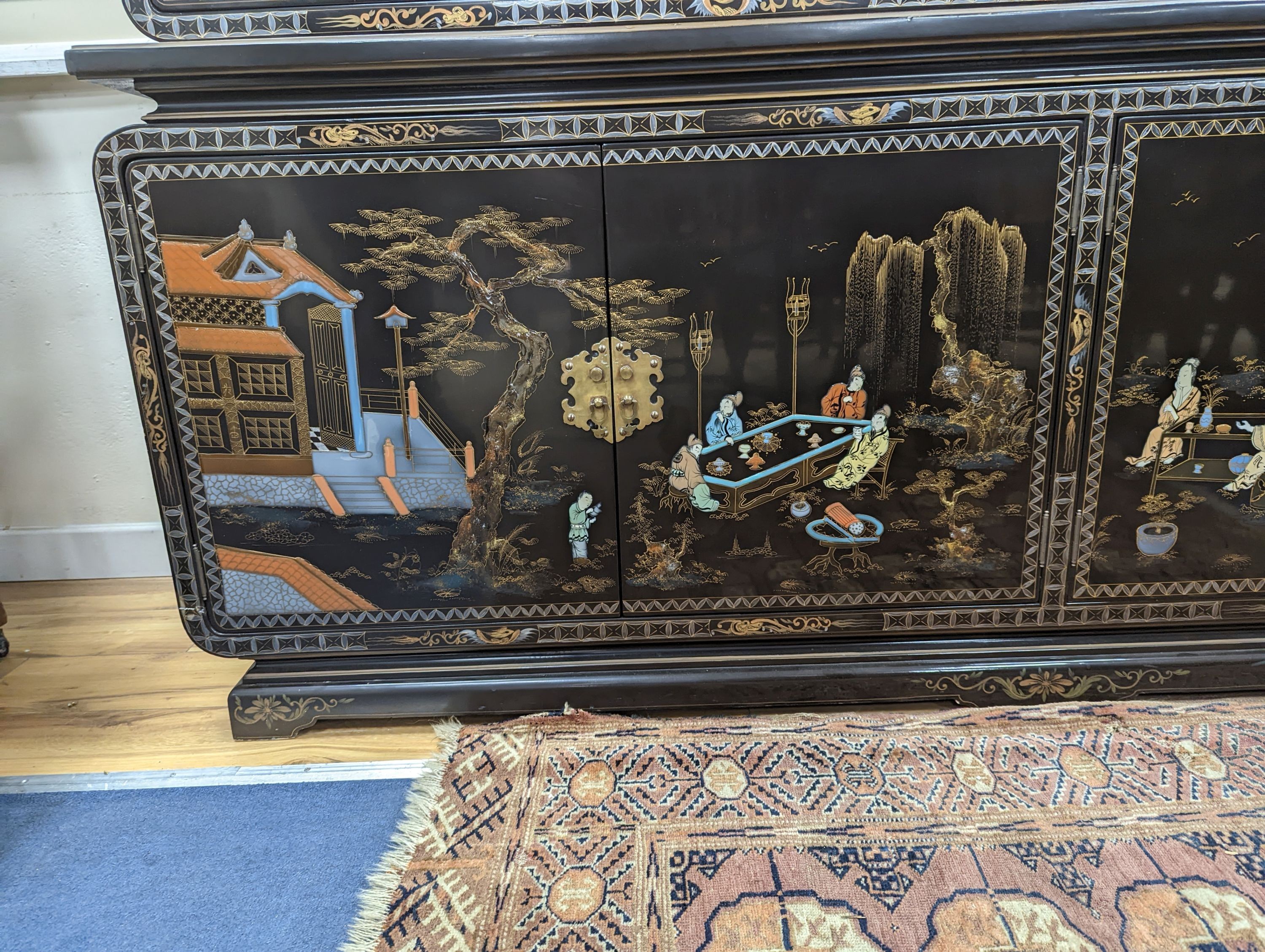 A Chinese lacquer decorated cabinet. W-200cm, D-45cm, H-201cm.